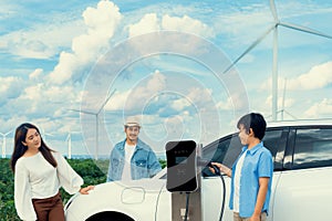Concept of progressive happy family at wind farm with electric vehicle.
