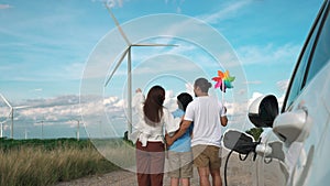 Concept of progressive happy family at wind farm with electric vehicle.