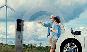 Concept of progressive happy family at wind farm with electric vehicle.