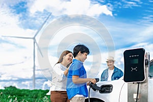 Concept of progressive happy family at wind farm with electric vehicle.