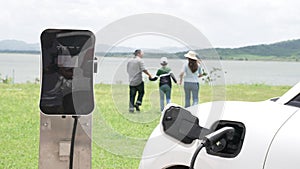 Concept of progressive happy family at wind farm with electric vehicle.