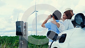 Concept of progressive happy family at wind farm with electric vehicle.