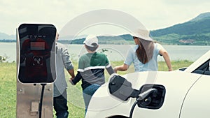 Concept of progressive happy family at wind farm with electric vehicle.