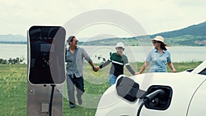 Concept of progressive happy family at wind farm with electric vehicle.