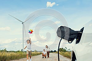 Concept of progressive happy family at wind turbine with electric vehicle.