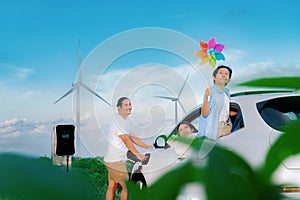 Concept of progressive happy family at wind turbine with electric vehicle.