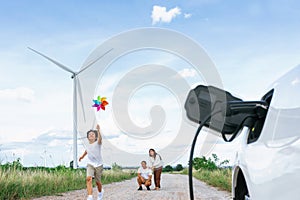 Concept of progressive happy family at wind turbine with electric vehicle.