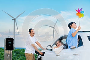 Concept of progressive happy family at wind turbine with electric vehicle.
