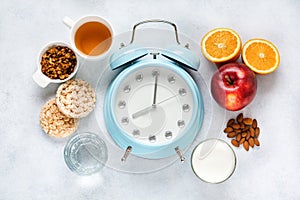 Concept of proper portioned nutrition for health calculated by the clock. Group useful breakfast coffee, tea, fruits, oats, nuts,