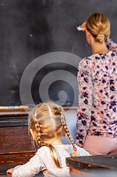 Concept of public primary school education with young girl listening to the female teacher