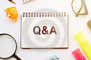 Concept Q and A message on notebook with glasses and magnifier on white background