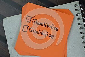 Concept of Quantitative or Qualitative write on a sticky notes isolated on Wooden Table