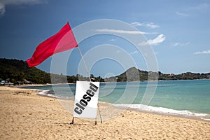 Concept quarantine, pandemic, coronavirus, travel ban. tropical beach on a sunny day without people. there is a red flag