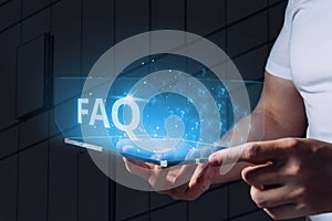 Concept of questions and answers or FAQ. A holographic display with icons is held by a person