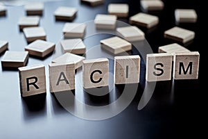 Concept of racism and misunderstanding between people, prejudice and discrimination. Wooden block with word racism on the black