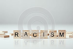 Concept of racism and misunderstanding between people, prejudice and discrimination. Wooden block with word racism on the white