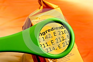 Concept of reading ingredients list on food package with magnifying glass.