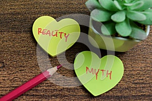 Concept of Reality or Myth write on sticky notes isolated on Wooden Table