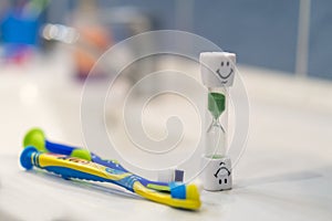 Concept of recommended time to brush your teeth. Soft focus. Two toothbrushes and hourglass. Brushing teeth for 3 Minutes