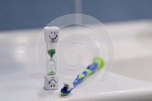 Concept of recommended time to brush your teeth. Soft focus. Two toothbrushes and hourglass. Brushing teeth for 3 Minutes