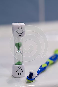 Concept of recommended time to brush your teeth. Soft focus. Two toothbrushes and hourglass. Brushing teeth for 3 Minutes.