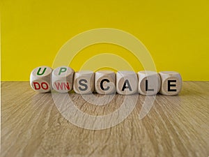 Concept red words Upscale or Downscale on wooden cubes. Beautiful wooden table yellow background. Business upscale or downscale