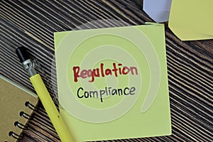 Concept of Regulation Compliance write on sticky notes isolated on Wooden Table