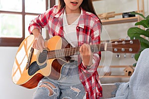 Concept of relaxation with music, Young asian woman practice playing chords with acoustic guitar