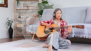 Concept of relaxation with music, Young asian woman wearing headphone and playing acoustic guitar