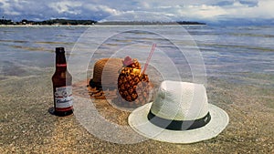 Concept of relaxing showing hats, pineapple juice with straw and abudweiser