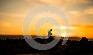 Concept of religion Islam. Silhouette of man praying on the background of a mosque at sunset