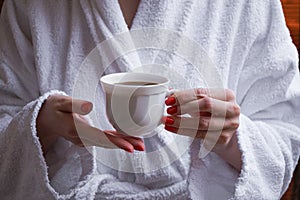 The concept of rest in a hotel. A cup in the hands of a girl in a white coat