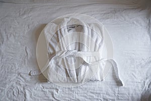 The concept of rest in a hotel. Terry white bathrobe on the bed, top view