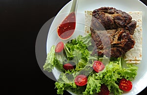 Concept for restaurant menu or food wallpaper with fried meat, greens and red sauce on a white plate in a side of image