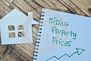 Concept of Rising Property Prices write on book isolated on Wooden Table