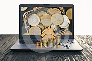 Concept of the sale and rental of housing, mortgage, loan. Lap top with blank screen and heap of euro coins, mock-up of a house