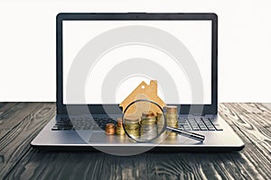 Concept of the sale and rental of housing, mortgage, loan. Lap top with blank screen and heap of euro coins, mock-up of a house