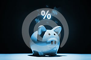The concept of savings and investment. Piggy bank with a hologram of charts and percentages.