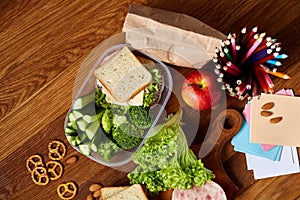 Concept of school lunch break with healthy lunch box and school supplies on wooden desk, selective focus.