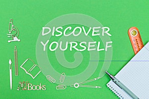 Text discover yourself, school supplies wooden miniatures, notebook with ruler, pen on green backboard