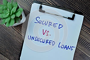 Concept of Secured Vs Unsecured Loans write on paperwork isolated on Wooden Table