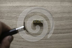 Concept of SEO. Selective focus of hand holding magnifying glass and look for gold alphabet beads of word SEO Search engine