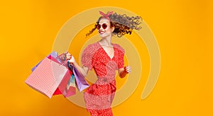 Concept of shopping purchases and sales of happy young girl with packages  on yellow background