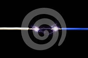 The concept of a short circuit. A spark or electric discharge of 10000 Volts occurs between the two wires. Dark background