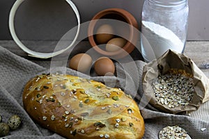 Concept shot of bread with a wooden spoon on the wood table, oatmeal and a skein of bag thread, egg, flour, seeds and nuts