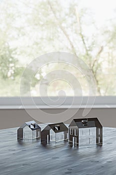 Concept shot: three differently sized glass models of houses on a table