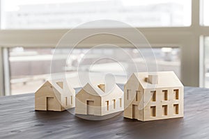 Concept shot: three differently sized wooden models of houses on an architects table