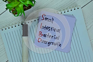 Concept of SIBO - Small Intestinal Bacterial Overgrowth write on sticky notes isolated on Wooden Table