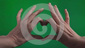 Concept or sign of love, silhouette. Slow motion Hands of woman or man made a heart shape at chroma key green abstract