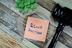 Concept of Silent Auction write on sticky notes with Gavel isolated on Wooden Table photo